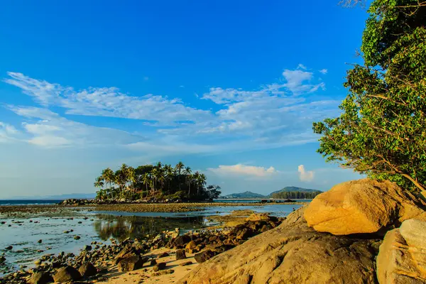寂寞的海岛与岩石海滩和树当海水消退在蓝天和多云天背景 — 图库照片