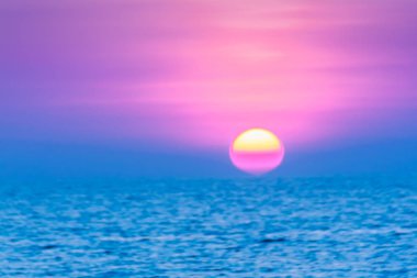 Beautiful sunset over the sea, view from the beach. Round and bright sun in dusk over calm sea  with blurred dramatic sky background. clipart