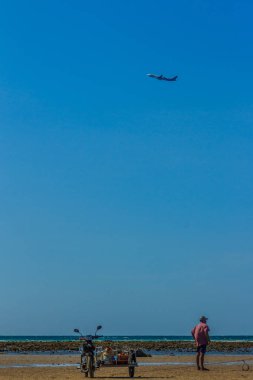 Balıkçı teknesini sonraki balığa için hazırlanması için sırayla tekneye alınan ekipman için motosiklet vagon gidiyordum. Onun tekne park sahilde mavi gökyüzü altında ve havaalanına yakın oldu