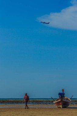 Balıkçı teknesini sonraki balığa için hazırlanması için sırayla tekneye alınan ekipman için motosiklet vagon gidiyordum. Onun tekne park sahilde mavi gökyüzü altında ve havaalanına yakın oldu