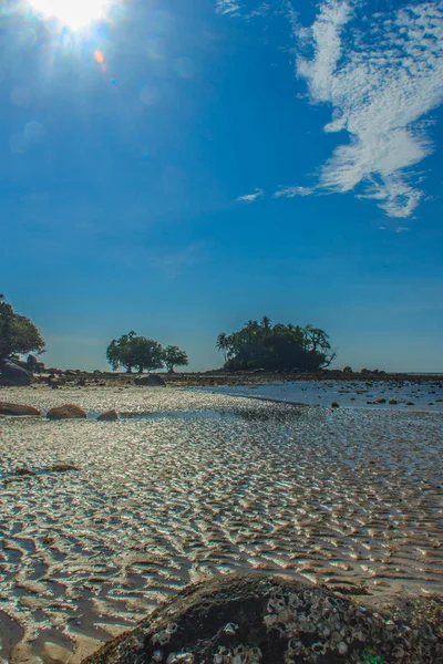 寂寞的海岛与岩石海滩和树当海水消退在蓝天和多云天背景 — 图库照片