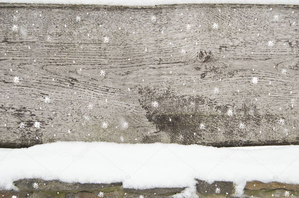 old dark wooden fence in snow. wood background with snowflakes.