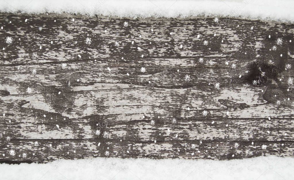 old dark wooden fence in snow. wood background with snowflakes.