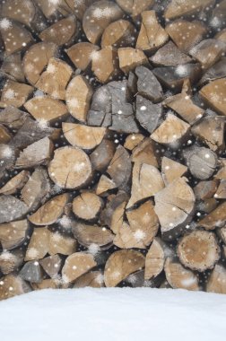 Yakacak odun, kışın kar altında depolanan günlük parçalar. Havada kar taneleri. Atmosferde tatil