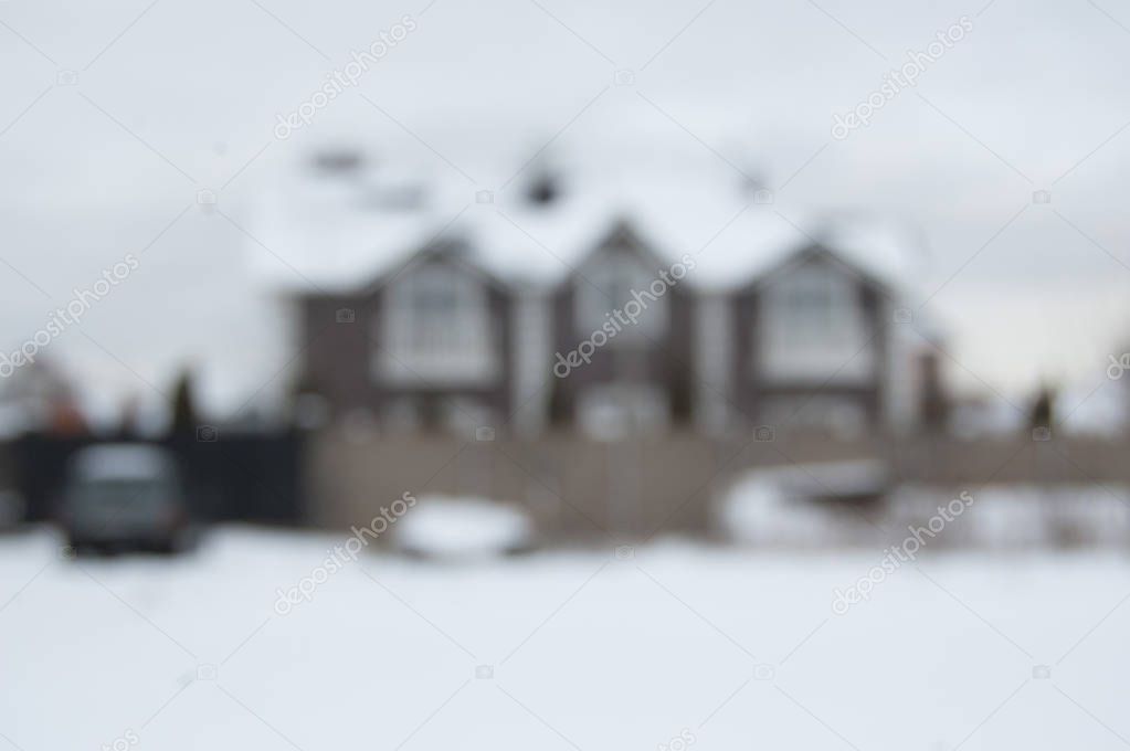 Blurry image. Defocused country house with car and fence in snow.
