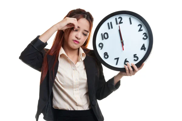 Sleepy young Asian business woman with a clock in the morning. Royalty Free Stock Images