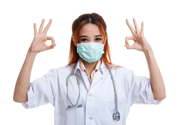 Jonge Aziatische vrouwelijke arts met masker show Ok met beide handen. — Stockfoto