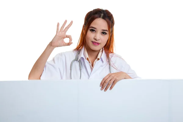 Junge asiatische weibliche Arzt zeigen ok Zeichen hinter leeren weißen Billb — Stockfoto