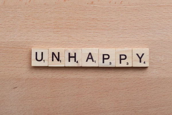 Scrabble brev stavning ordet olycklig. — Stockfoto