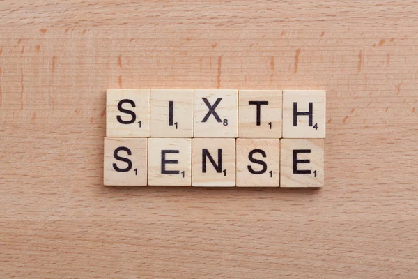 Scrabble letters spelling the word sixth sense.