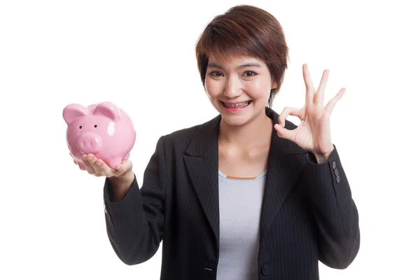 Asiatische unternehmerin zeigen ok mit schwein coin bank. — Stockfoto