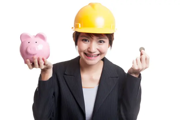 Aziatische ingenieur vrouw met een munt en piggy munt bank. — Stockfoto