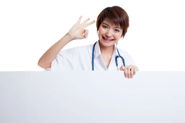 Young Asian female doctor show OK sign  behind blank white billb — Stock Photo, Image