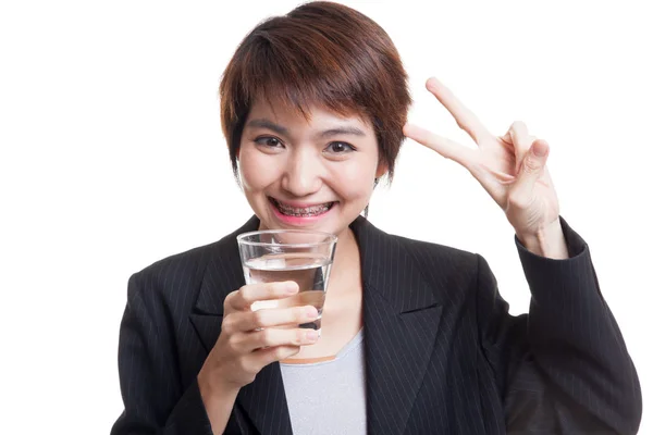 Junge Asiatin zeigt Siegeszeichen mit einem Glas Trinkwasser — Stockfoto
