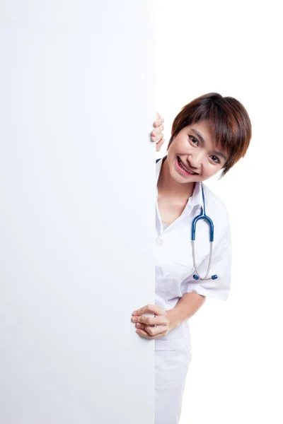 Young Asian female doctor peeking from behind blank sign billboa — Stock Photo, Image