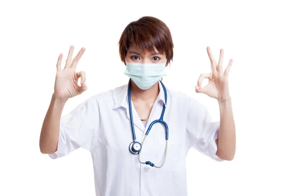 Jonge Aziatische vrouwelijke arts met masker show Ok met beide handen. — Stockfoto