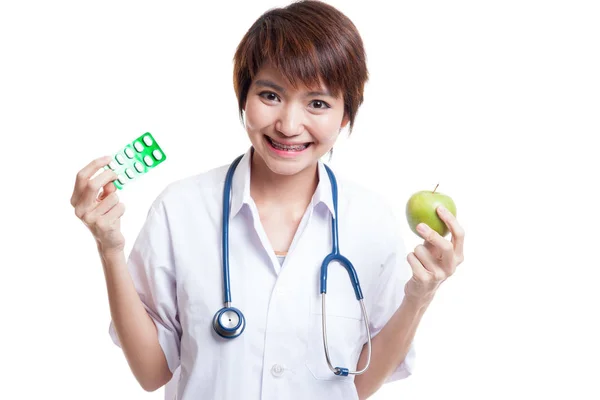 Unga asiatiska kvinnliga läkare med piller och äpple. — Stockfoto