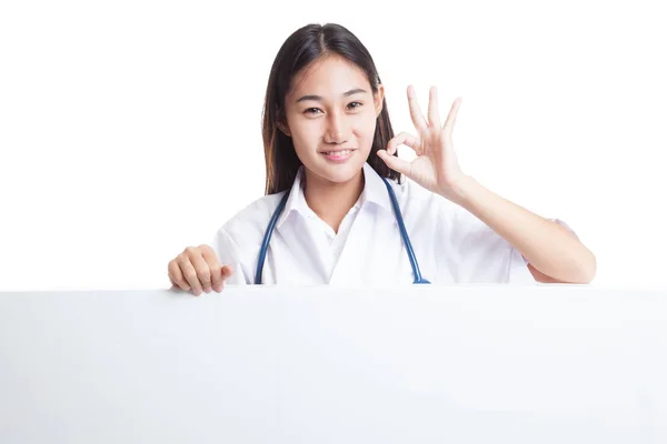 Young Asian female doctor show OK sign  behind blank white billb — Stock Photo, Image