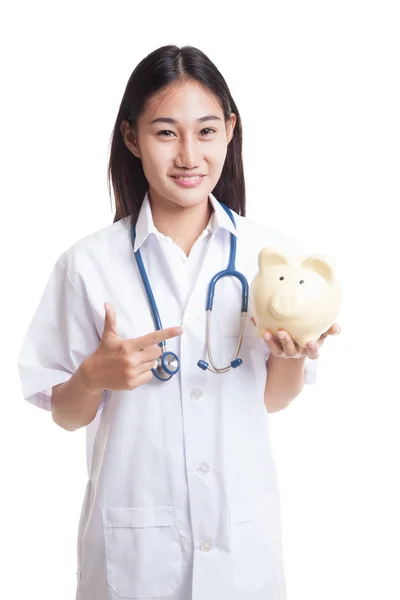 Young Asian female doctor point to a pig bank coin. — Stock Photo, Image