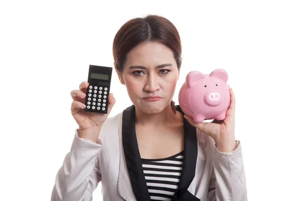 Unhappy Asian business woman with calculator and piggy bank. — Stock Photo, Image