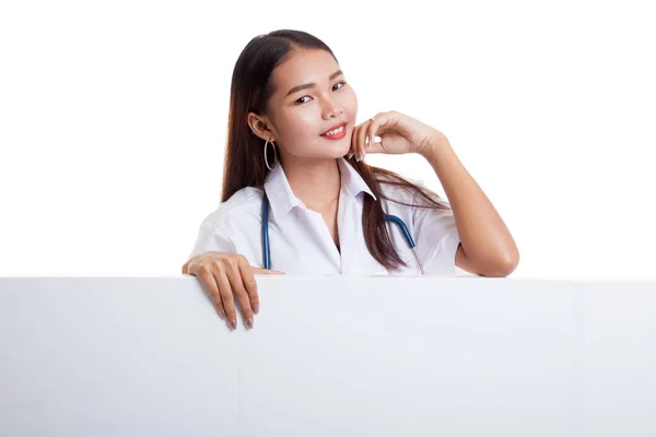 Young Asian female doctor standing behind blank white billboard. — Stock Photo, Image