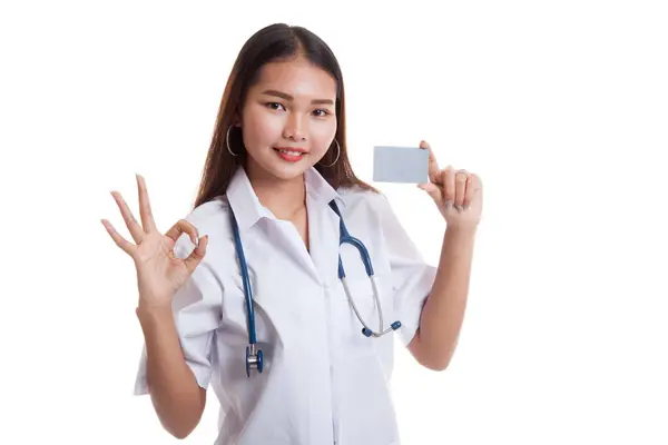 Asiática joven médico mostrar Ok signo con tarjeta en blanco . — Foto de Stock