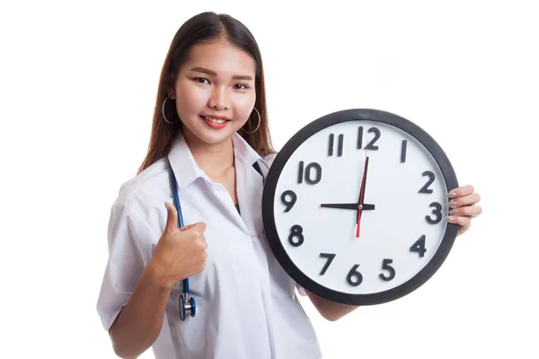 Unga asiatiska kvinnliga läkare tummen upp med en klocka. — Stockfoto