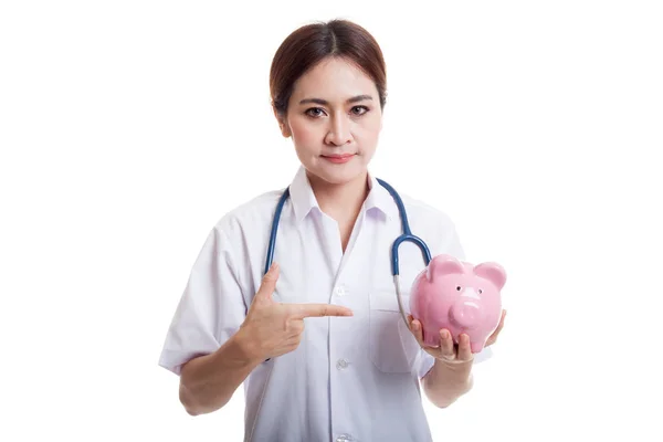 Young Asian female doctor point to a pig bank coin. — Stock Photo, Image
