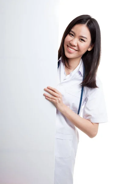 Jovem asiático médico feminino espreitando por trás sinal em branco billboa — Fotografia de Stock