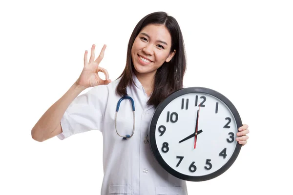 Jeune asiatique femme médecin montrer OK avec une horloge . — Photo