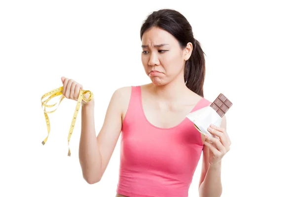 Olyckliga asiatiska friska flicka med choklad och mäta tejp. — Stockfoto