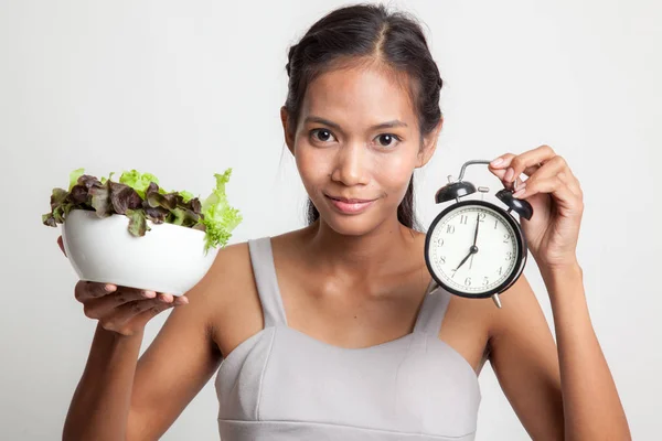 Ung asiatisk kvinna med klocka och sallad. — Stockfoto