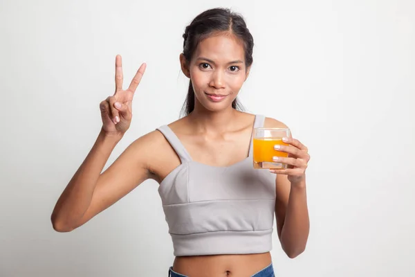 Jovem mulher asiática mostrar vitória sinal bebida suco de laranja . — Fotografia de Stock