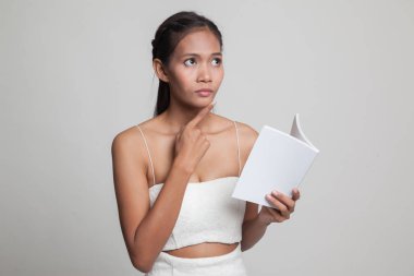 Bir kitapla genç Asyalı kadın düşünüyor.