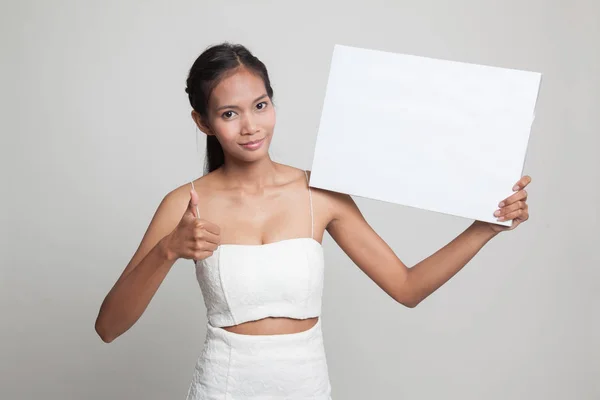 若いアジア女性は白い空白記号と親指を表示します。. — ストック写真