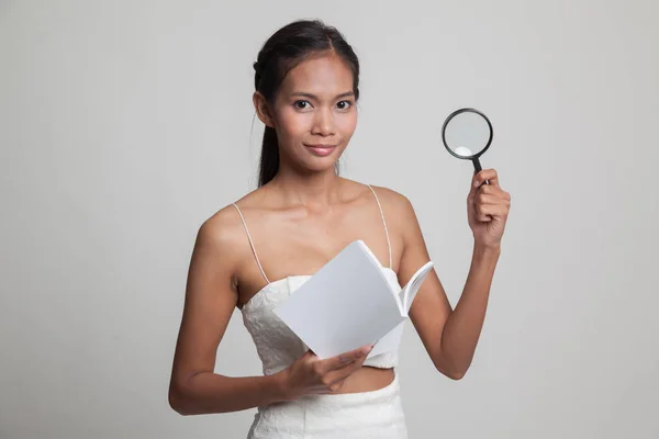 Asian woman with a book and magnifying glass. — Stock Photo, Image