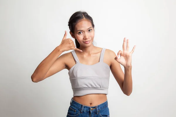 Joven asiático mujer espectáculo con el gesto del teléfono y OK signo . —  Fotos de Stock