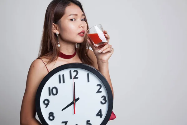 Ung asiatisk kvinna med tomatjuice och klocka. — Stockfoto