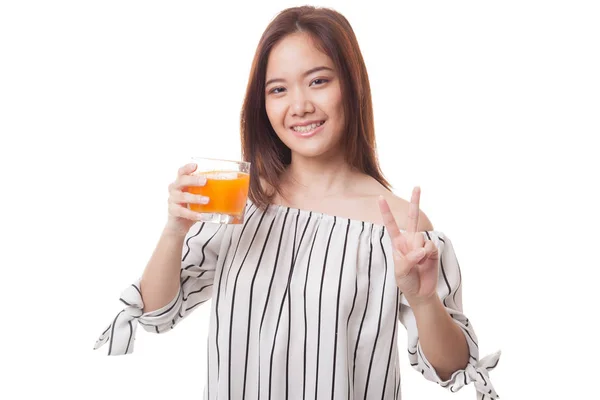 Junge asiatische Frau zeigt Siegeszeichen trinken Orangensaft. — Stockfoto