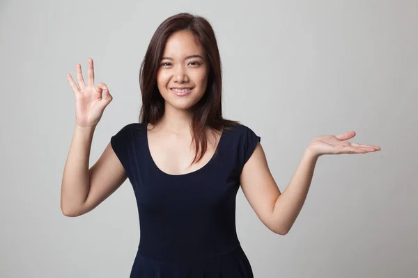 Schön junge asiatische Frau zeigen Handfläche Hand und ok Zeichen. — Stockfoto