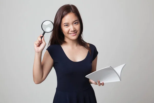 Asian woman with a book and magnifying glass. — Stock Photo, Image