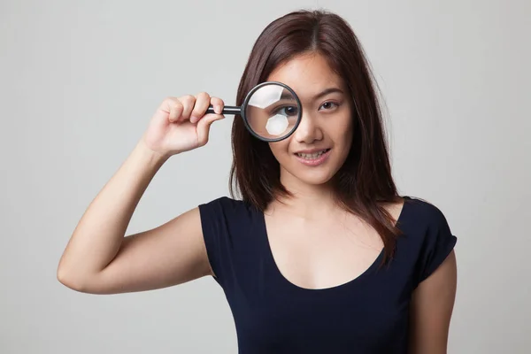 Young Asian woman with a magnifying glass. — Stock Photo, Image