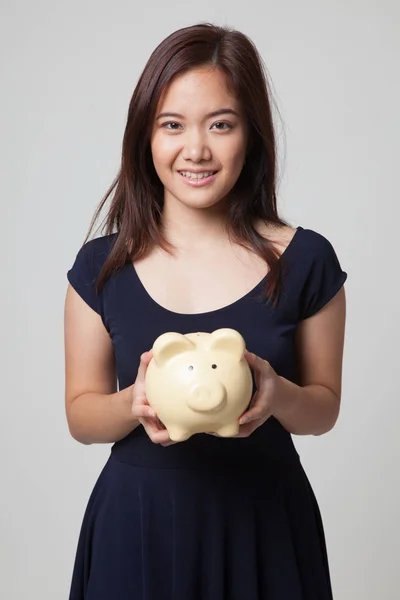Fiatal ázsiai nő, egy disznó érme bank. — Stock Fotó