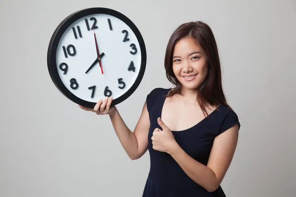 Young Asian woman thumbs up with a clock. — Stock Photo, Image