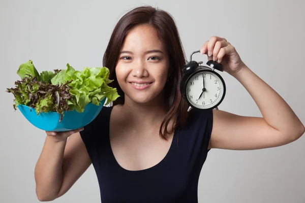 Ung asiatisk kvinna med klocka och sallad. — Stockfoto