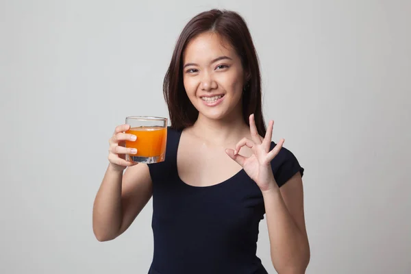 Ung asiatisk kvinna drink apelsin juice visar Ok tecken. — Stockfoto