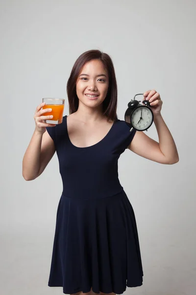 Asiatisk kvinna med en klocka drink apelsin juice. — Stockfoto