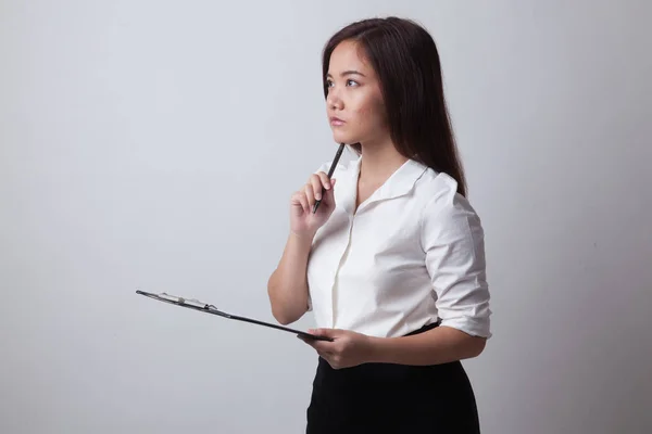 Junge asiatische Geschäftsfrau denkt mit Stift und Klemmbrett. — Stockfoto