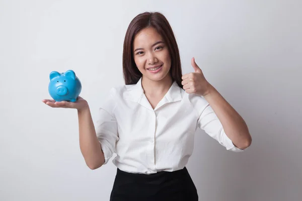 Aziatische vrouw duimen omhoog met varken munt bank. — Stockfoto