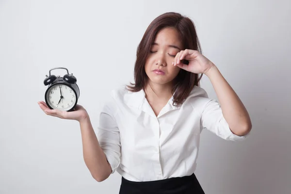 Schläfrige junge asiatische Frau mit einer Uhr am Morgen. — Stockfoto